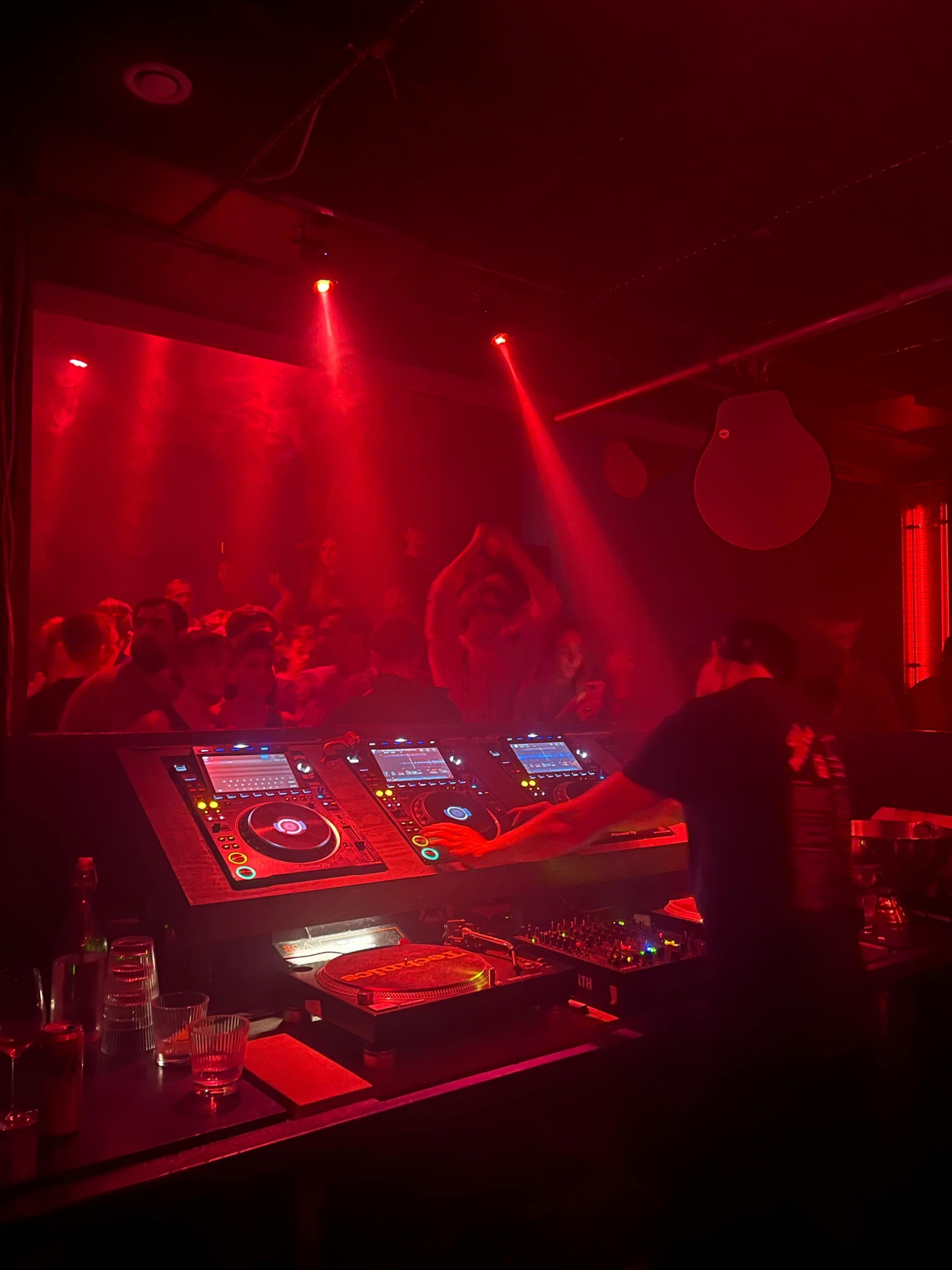 DJ booth and crowd under red club lights