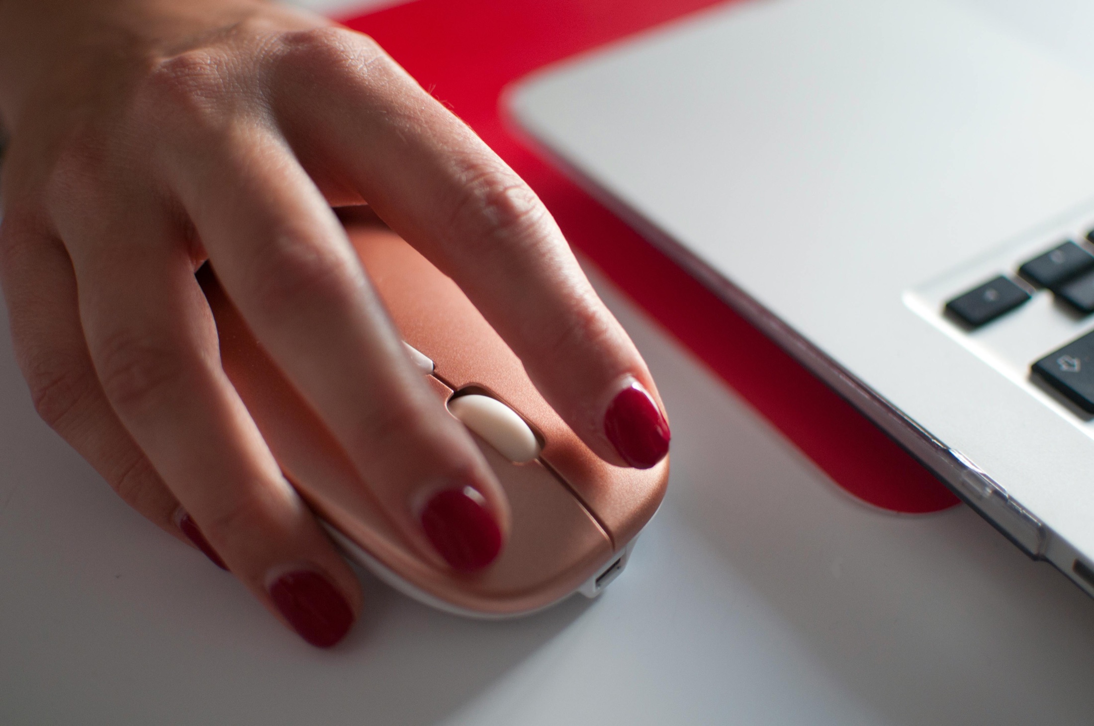 Hand using a computer mouse beside a laptop